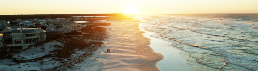 Aerial view of Grayton Beach at sunset, with soft sand dunes and gentle waves along Florida’s scenic Gulf Coast.