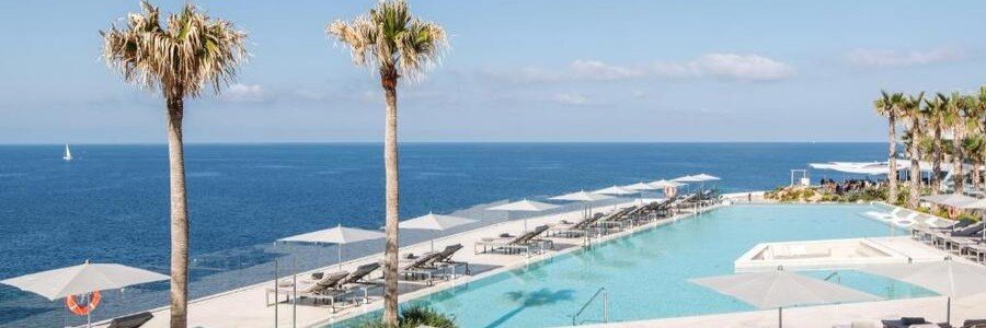 Glass-walled infinity swimming pool overlooking the Mediterranean Sea at 7Pines Resort Ibiza