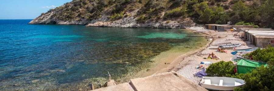 Secluded beach and traditional fishermen huts at Cala Llentrisca quiet hidden gem in Ibiza