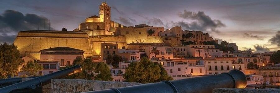 Illuminated historic fortress walls and cathedral of Dalt Vila at sunset in Ibiza Old Town