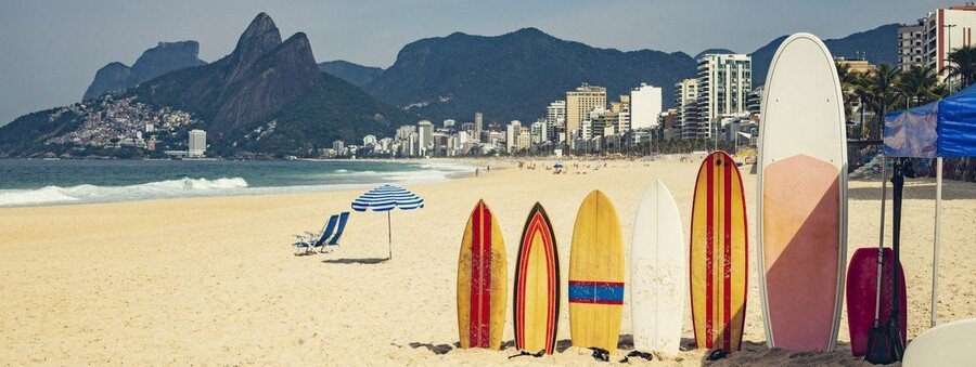 Colorful surfboards lined up on Ipanema Beach with Dois Irmãos mountains in Rio de Janeiro Brazil