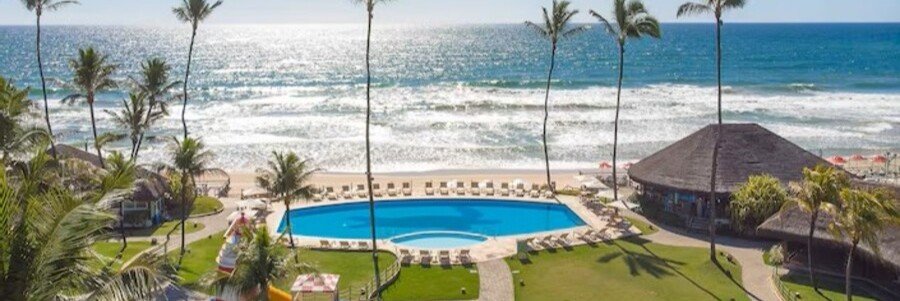 Oceanfront swimming pool and tropical gardens at Armação Resort Porto de Galinhas overlooking the beach in Pernambuco, Brazil.