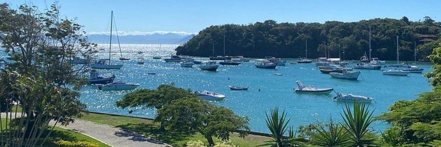 Búzios Harbor and Scenic Coastal Views Sailboats and fishing boats anchored in a blue coastal bay surrounded by green hills in Búzios, Brazil.
