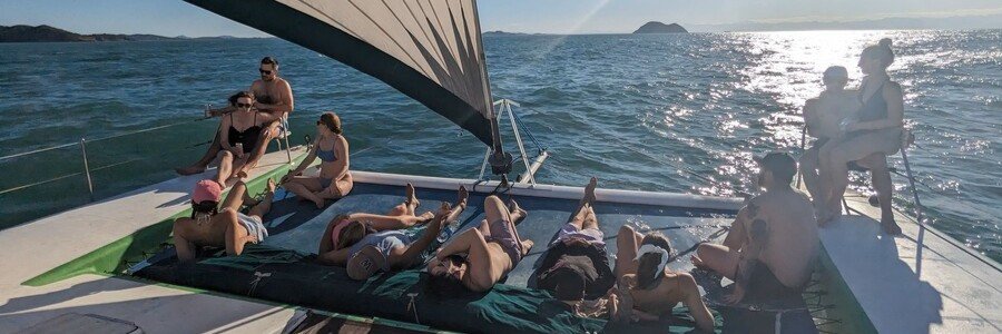 Catamaran Sailing Tour in Búzios | Beach Travel Destinations Travelers relaxing aboard a catamaran during a sailing tour in Búzios, Brazil.