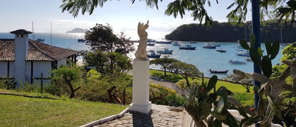 View from Church of Sant'Anna in Buzios Brazil showing an angel statue over an ocean bay filled with boats