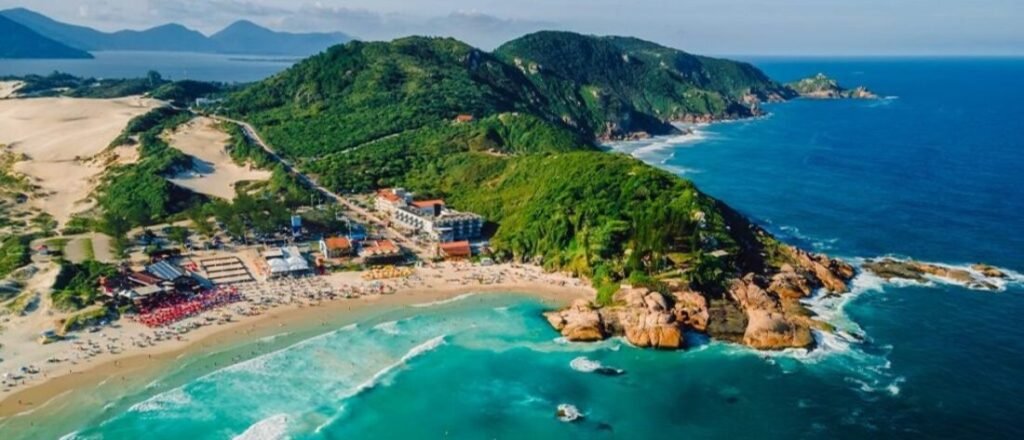 High aerial view of Praia da Joaquina in Florianopolis Brazil showing iconic sand dunes rocky point and turquoise surf