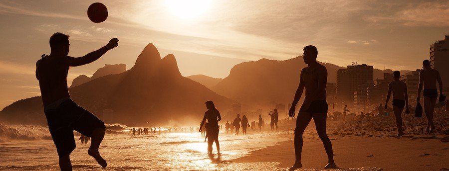 People playing footvolley at sunset on Ipanema Beach with Dois Irmãos mountains in Rio de Janeiro Brazil