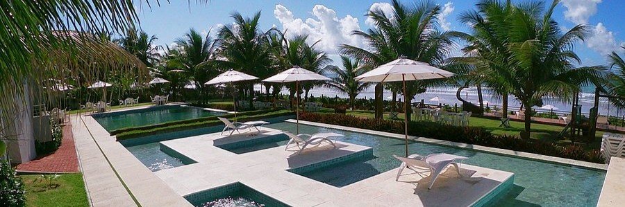 Modern outdoor pool surrounded by palm trees at Hotel Pousada Butias near the beach in Porto de Galinhas, Brazil.