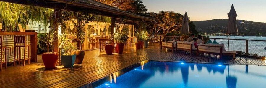 Insólito Boutique Hotel & Spa Poolside Terrace Illuminated swimming pool and wooden terrace overlooking Ferradura Beach at Insólito Boutique Hotel & Spa in Búzios.