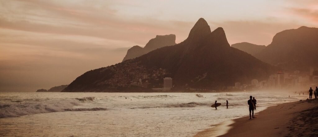 Sunset over Ipanema Beach with surfers and Dois Irmãos mountains in Rio de Janeiro Brazil