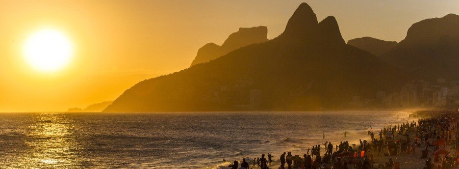 Sunset over Ipanema Beach with crowds and Dois Irmãos mountains in Rio de Janeiro Brazil