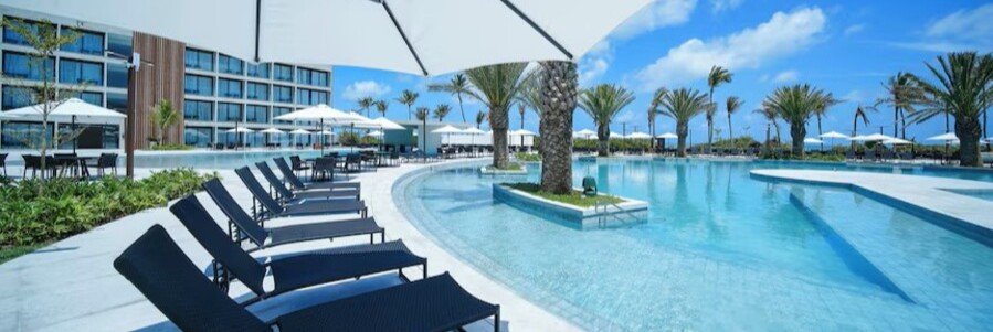 Large resort-style swimming pool with lounge chairs and palm trees at Porto 2 Life Gav Resorts in Porto de Galinhas.
