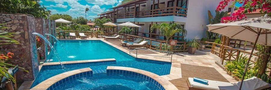 Swimming pool at Pousada Carcará in Jericoacoara surrounded by sun loungers and tropical gardens.