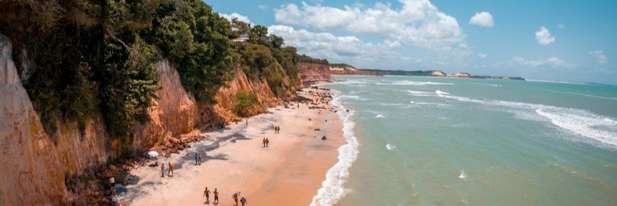 Aerial panorama of Praia do Amor in Pipa Brazil showing steep red sandstone cliffs and ocean coastline