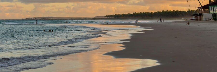 Golden sunset reflecting across the shoreline at Praia da Pipa, Brazil.