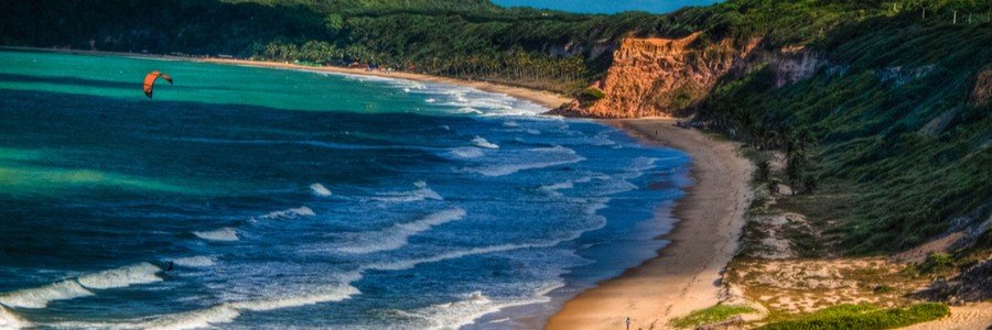 Praia do Madeiro with golden cliffs, turquoise water, and a sandy beach near Praia da Pipa.