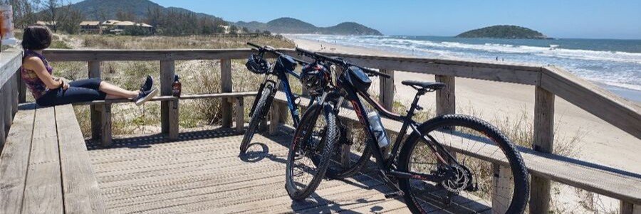 Bicycles parked beside a beach boardwalk overlooking the coastline near Praia do Rosa.