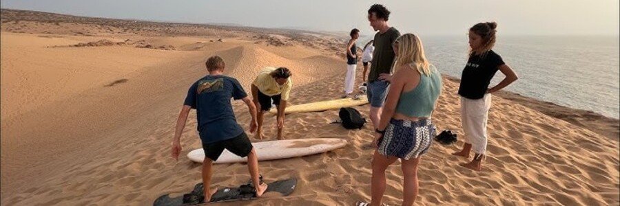 Sandboarding on Coastal Dunes Florianopolis | Beach Travel Destinations Visitors learning to sandboard on towering coastal sand dunes overlooking the ocean.
