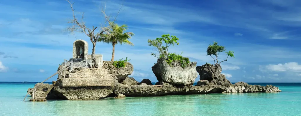 Willy’s Rock Shrine standing in shallow turquoise water beneath a bright blue sky in Boracay.