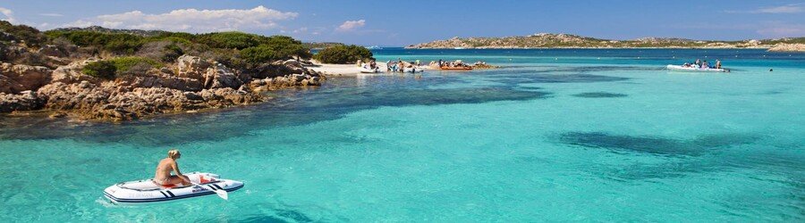 turquoise water and small boat near rocky coast in Sardinia
