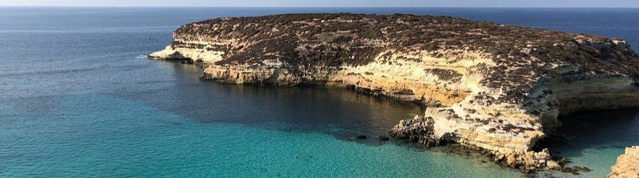 Rocky coastline and clear blue water at Cala Galera in Lampedusa, Italy