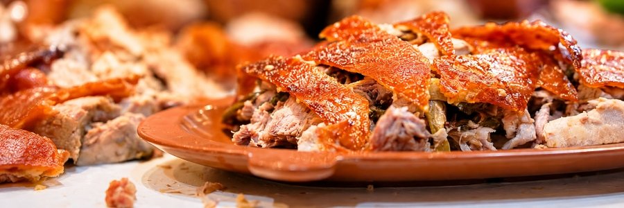 Traditional Filipino Cebu lechon featuring golden, crispy roasted pork skin and tender, juicy meat served on a rustic terracotta platter.