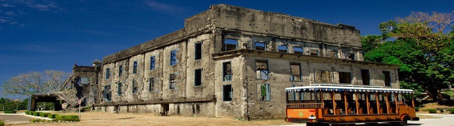 Historic ruins on Corregidor Island with sightseeing tram in front