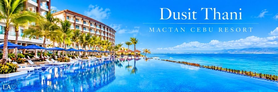 Spectacular oceanfront infinity pool lined with tropical palm trees, blue umbrellas, and elegant sun loungers overlooking sparkling turquoise water and distant mountains.