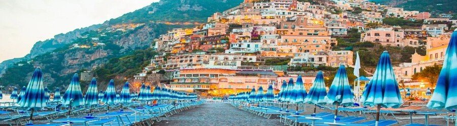 Spiaggia Grande in Positano Italy with rows of blue umbrellas and colorful cliffside buildings