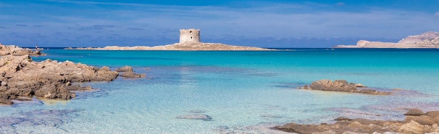 Turquoise beach in Sardinia with a historic stone tower and rocky coastline