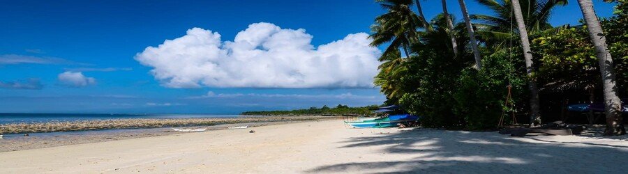 Solangon Beach in Siquijor, Philippines, with white sand, palm trees, calm shallow water, and a quiet tropical shoreline