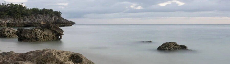 Quiet rocky beach on Malapascua Island in Cebu, Philippines with calm sea and coastal cliffs