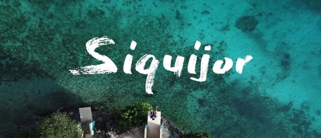 Aerial view of Siquijor Island in the Philippines with turquoise waters, coral reefs, and the word “Siquijor” overlaid on the ocean