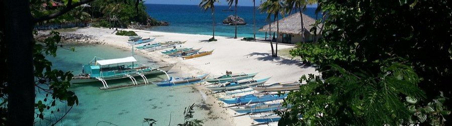 Boats along Thresher Cove Beach on Malapascua Island with clear water