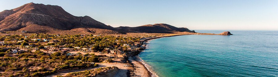 Aerial view of Cabo San Lucas coastline with desert hills meeting turquoise waters along the Baja