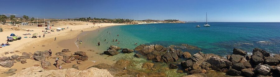Swimmers and snorkelers enjoying the calm turquoise waters and golden sands of Chileno Beach in Cabo San Lucas.
