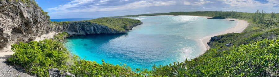 Panoramic view of Dean’s Blue Hole on Long Island with dramatic cliffs and deep blue water.