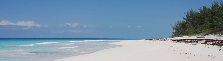 White sand beach and calm turquoise water with rocky outcrops at Gaulding Cay Beach.