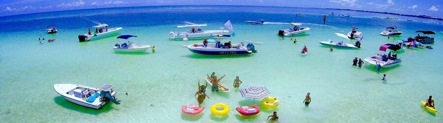 Boats anchored at the Islamorada Sandbar with people relaxing in shallow turquoise water