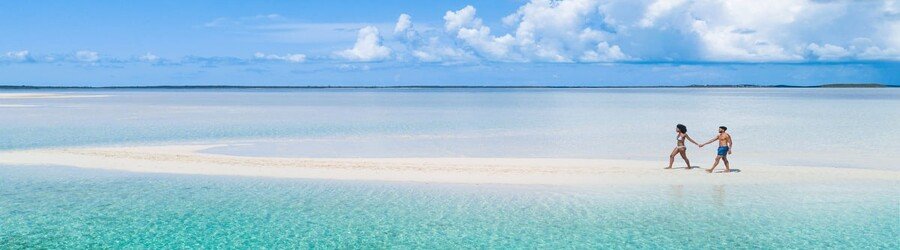 Beachgoers enjoying clear turquoise water and white sand at Junkanoo Beach near downtown Nassau.