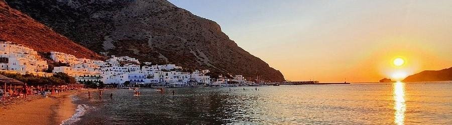 Sunset at Kamares Beach Sifnos with golden light, sandy beach, and hillside village.