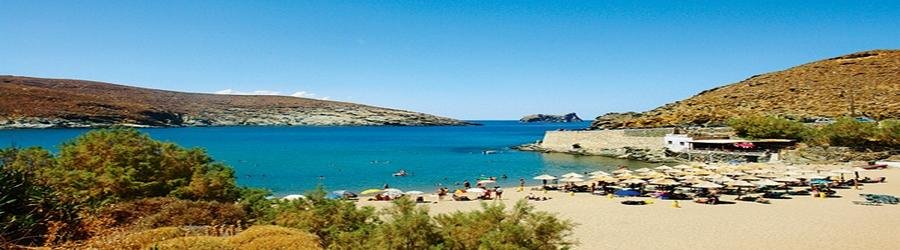 Kolympithra Beach on Tinos with umbrellas and swimmers enjoying the calm bay.