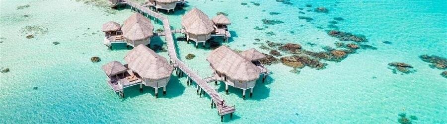 Overwater bungalows above a clear turquoise lagoon at Le Tikehau by Pearl Resorts