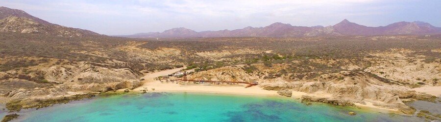 Aerial view of a secluded turquoise cove surrounded by rocky desert terrain along the Sea of Cortez.