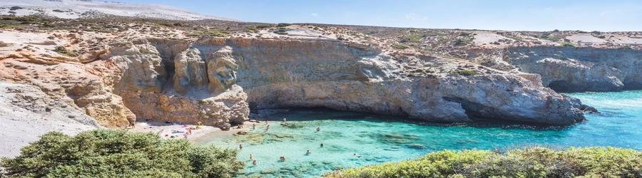 Hidden cove beach surrounded by towering cliffs and turquoise waters in Milos, Greece.
