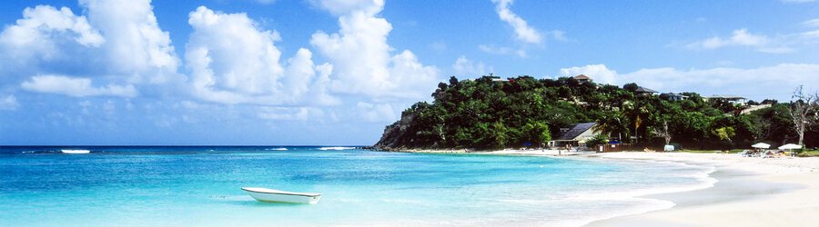 White-sand beach with calm turquoise water and a small boat along the coast of Puerto Rico.