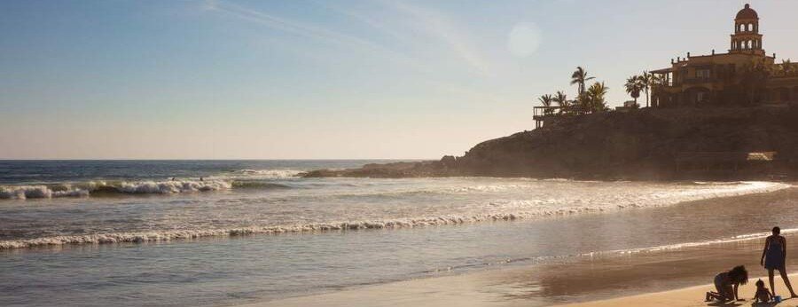 Playa Los Cerritos beach in Baja California Sur Mexico with waves rolling onto sandy shore and coastal resort buildings on a sunny day
