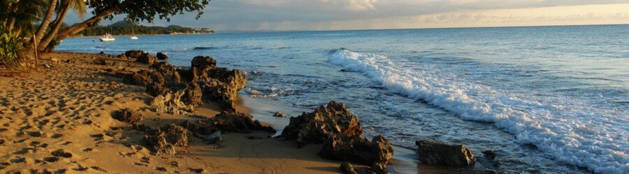 Rocky shoreline in Rincón, Puerto Rico, during golden hour with waves washing over the coast.