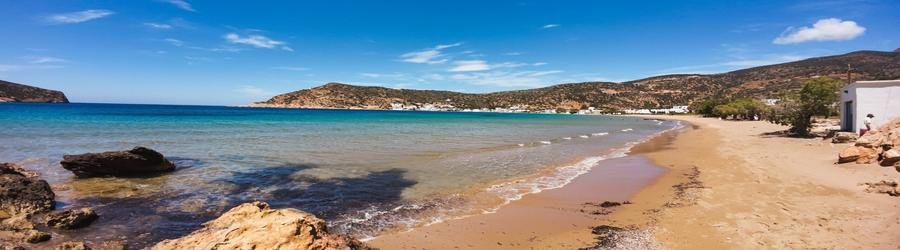 Wide view of Sifnos beaches with turquoise sea, hills, and whitewashed houses.