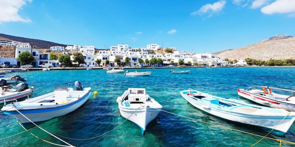 Scenic harbor of Tinos, Greece with fishing boats, whitewashed houses, and hills, showcasing the most beautiful Tinos in the Cyclades.